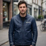 Person wearing the Moskvitch Leather Jacket outdoors, front-facing, showing cream 'moskvitch' wordmark embroidered on the left chest